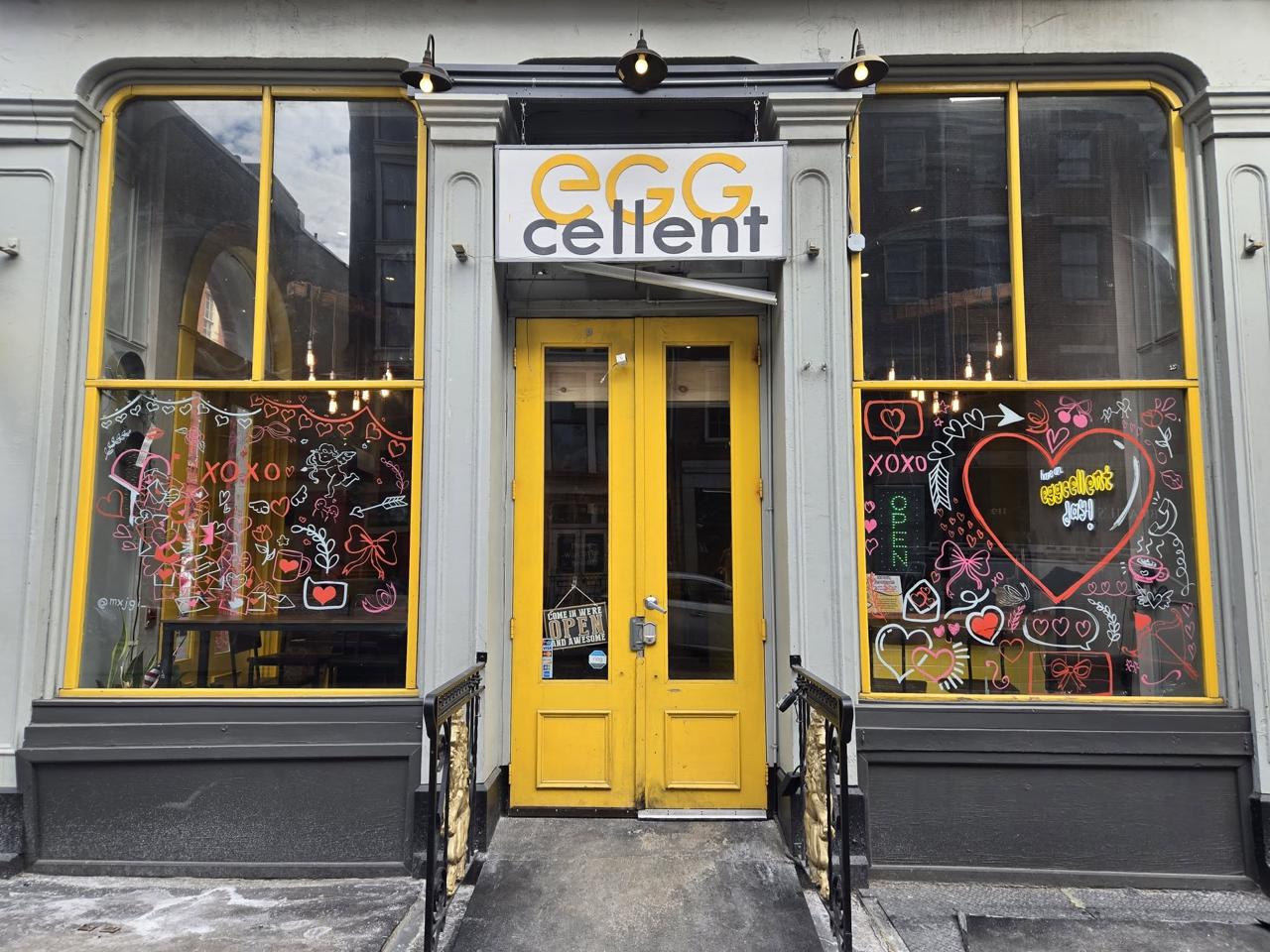 Eggcellent Cafe storefront with bright yellow doors and artistic window displays